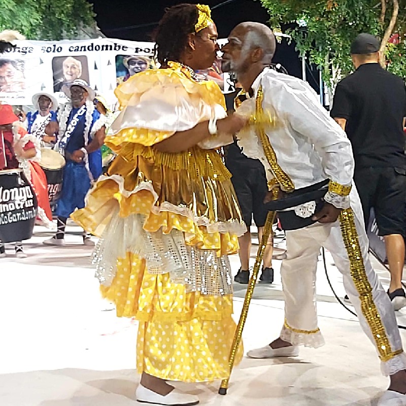 An image of male and female Candombe characters in white and yellow costumes